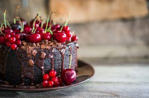 Chocolate cake with cherries on wooden background